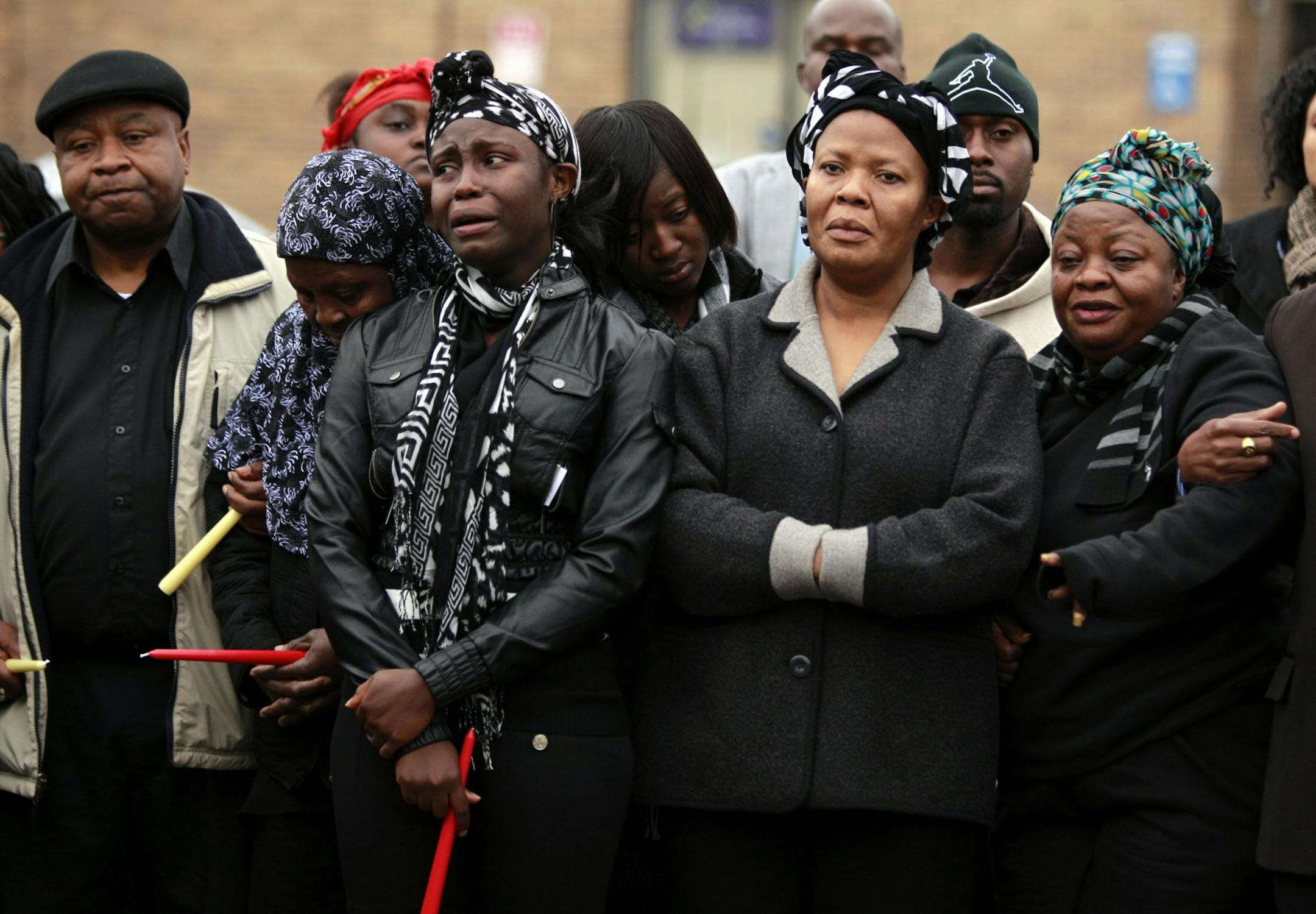 FILE -- Victoria Gbojueh, second from right, mourned with family and friends during a vigil for Gbojueh's sister Beatrice Wilson and Wilson's grandson Peter Wilson on Sunday, Nov. 4, 2012, outside the house where the double murder took place in Minneapolis.