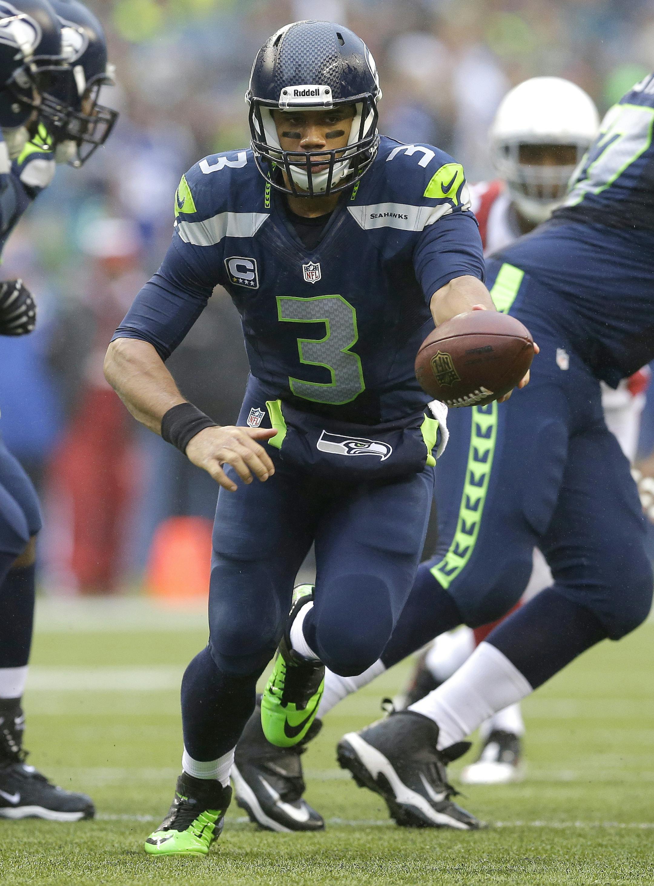 Seattle Seahawks quarterback Russell Wilson (3) prepares to hand off the ball against the Arizona Cardinals in the first half of an NFL football game, Sunday, Dec. 22, 2013, in Seattle. (AP Photo/Elaine Thompson)