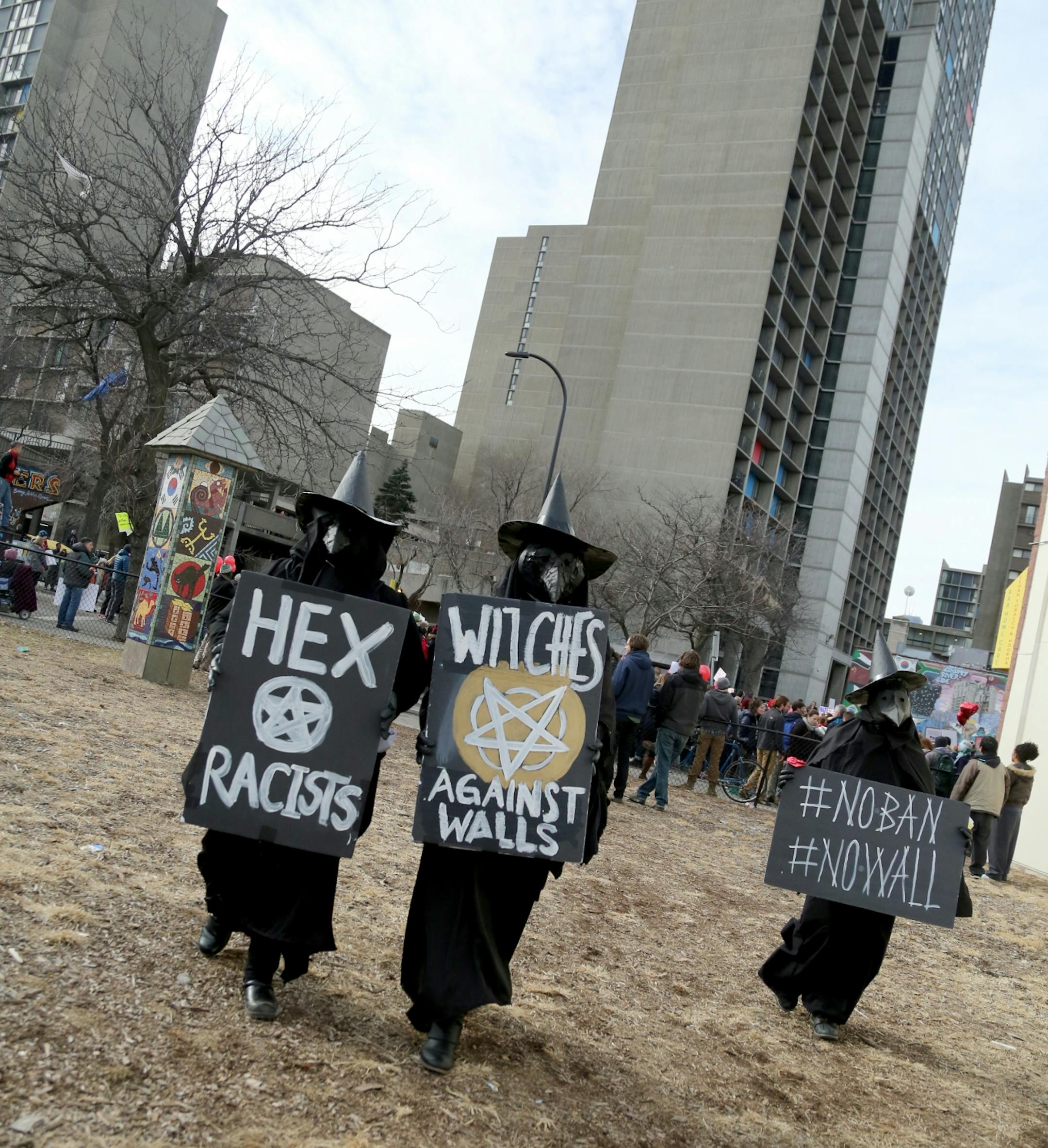 A group of women dressed in black with witches signs check out the Cedar-Riverside apartment during The Caravan of Love: A Walk of Love for Immigrants and Refugees Saturday, Feb. 11, 2016, in Minneapolis, MN.