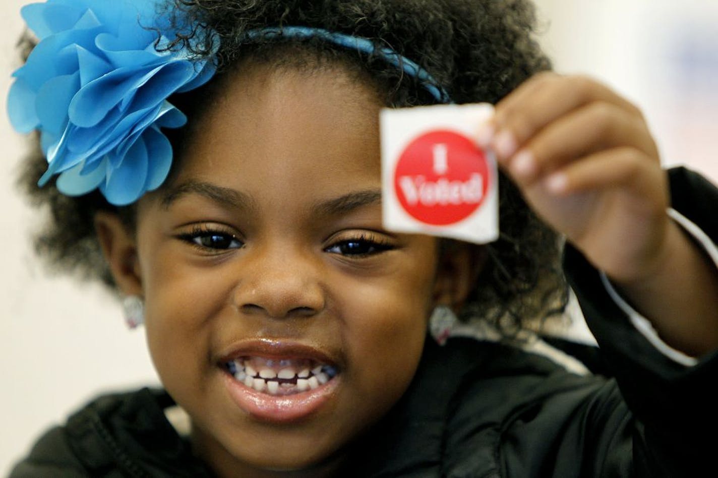 Lauren Miller, 5, left, was more than happy to hold up her mother Quinne Miller 's "I voted" sticker at the first precinct at the Urban Research and Outreach Center in North Minneapolis, MN, early Tuesday, November 6, 2012. The precinct judge said there were at least 200 people who voted by 8 a.m. (ELIZABETH FLORES/STAR TRIBUNE) ELIZABETH FLORES � eflores@startribune.com
