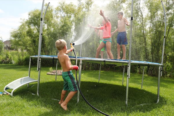 Rusty Golaski, center, 5, sprayed his siblings with a hose as they spent the afternoon playing with their friends on the family's trampoline, despite 