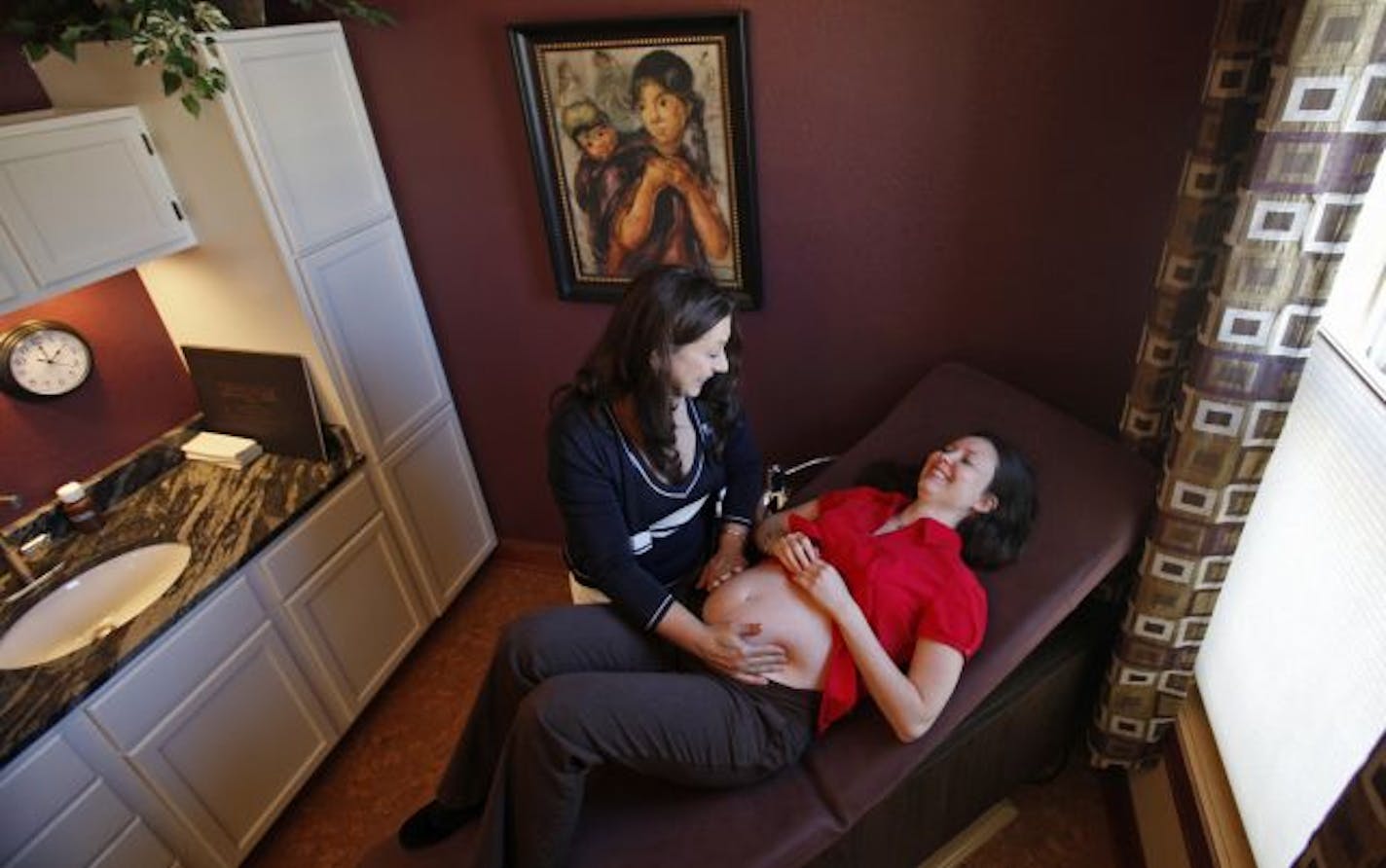 Midwife Paula Bernini Feigal examined Phala Tracy of Minneapolis, who is almost 26 weeks along, at Morning Star Birth Center in St. Louis Park. While state law now requires Medicaid to pay for births at such centers, insurers don't cover them.