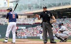 Minnesota Twins batter Brian Dozier, left, looks to the Detroit Tigers dugout as plate umpire Hal Gibson warns the Tiger bench after they complained a