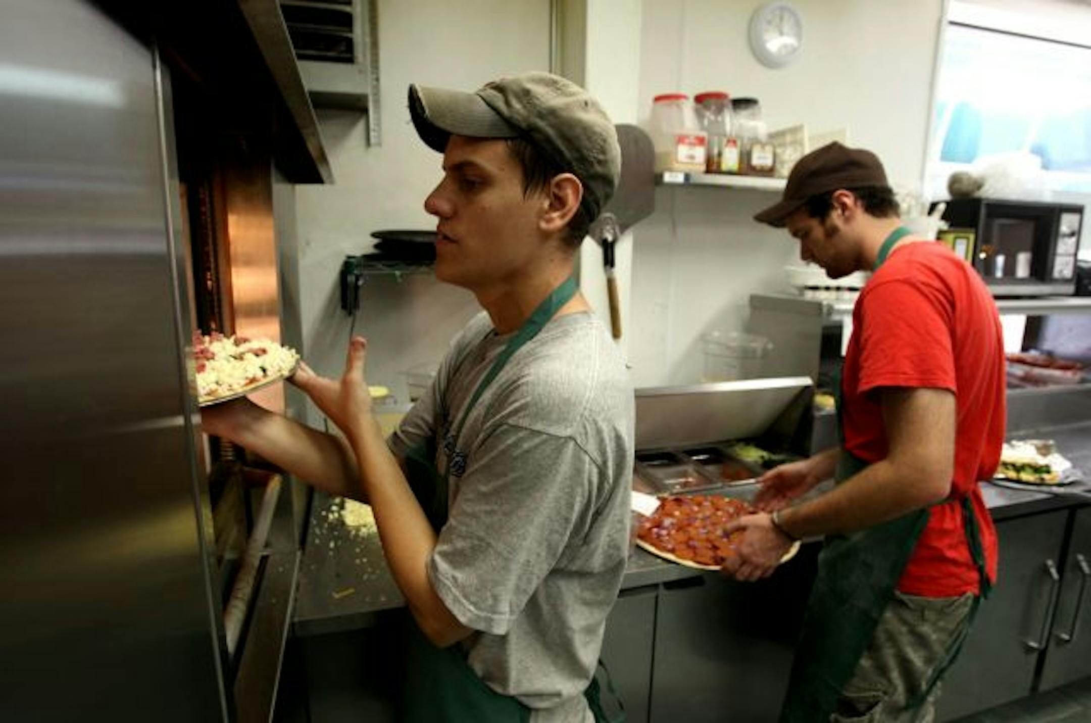 Parkway Pizza workers Ryan Holmstrom, left, and John Cliffer work the evening rush at the Longfelllow pizza joint that was recently slapped with an $8,000 sewer hookup fee.