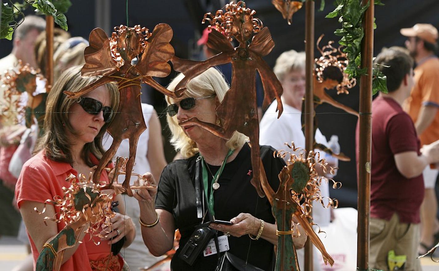 BRUCE BISPING � bbisping@startribune.com Minneapolis, MN., Friday, 8/3/2007. (left to right) Julie Stensrud of Bloomington looked at copper sculptures as artist Alice Calhoun of Herman MO. pointed out details of her work. This is the 8th year the Missouri artist has exhibited at the Uptown Art Fair which opened Friday afternoon and runs through Sunday. The fair features art, live music, food, juried art and childrens activities and is free to attend.