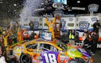 Kyle Busch, center, celebrated under the lights after winning the NASCAR Cup series auto race at Martinsville Speedway in Martinsville, Va., on Sunday