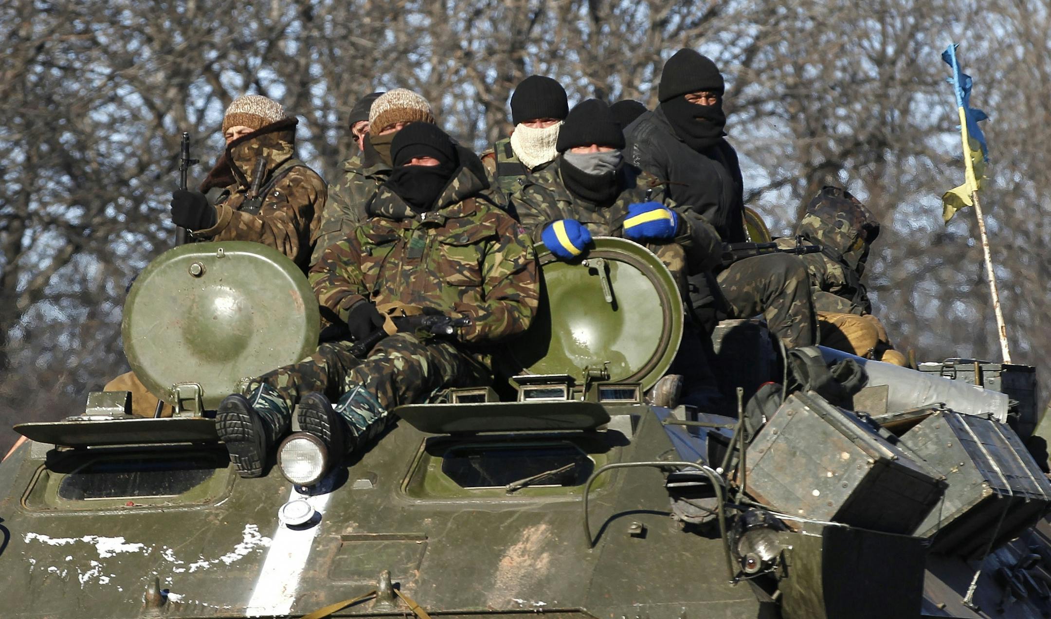 Ukrainian government soldiers sit on top of their armored vehicle driving on a road stretching away from the town of Artemivsk, Ukraine, Tuesday, Feb. 17, 2015.
