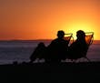 A couple sitting on a California beach at sunset. istock