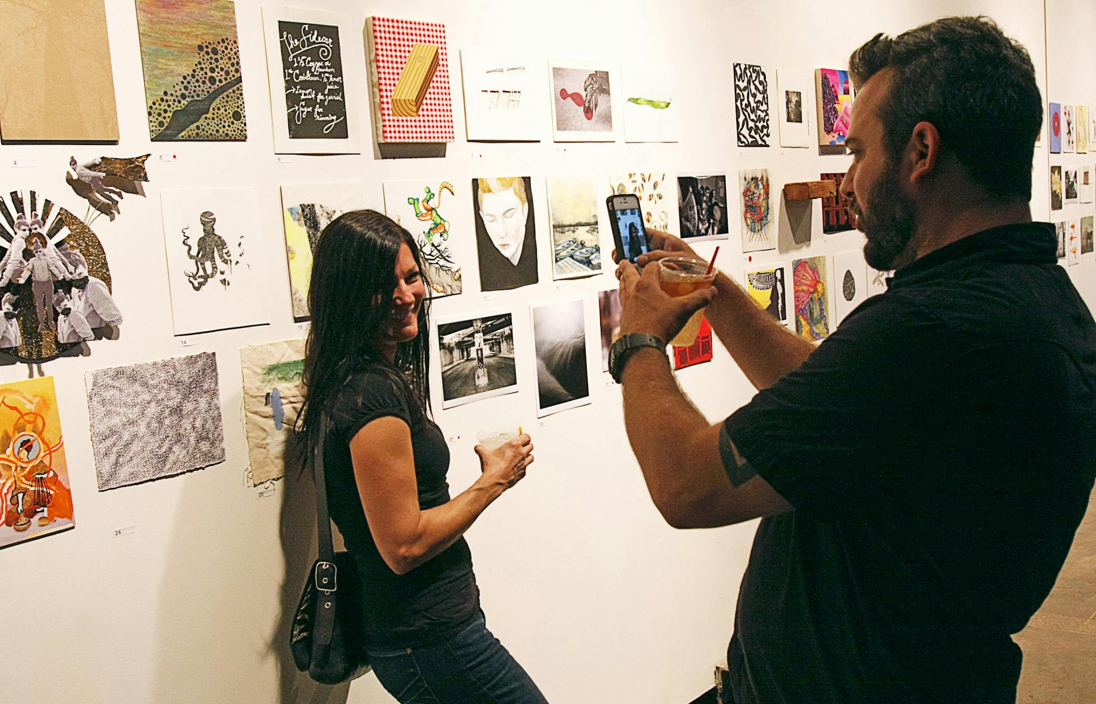 Adam Harness snaps a photo of Julie Wengler in front of the wall of artwork on sale during the 8th Annual $99 Art Sale at the Soap Factory gallery in Northeast Minneapolis on September 27.
