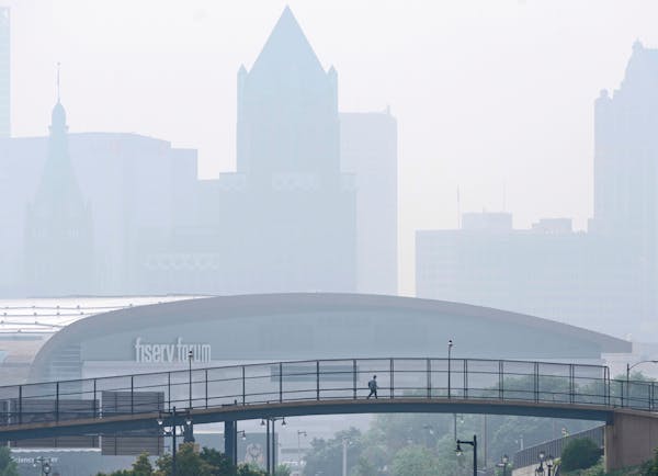 Alexander Balestrieri of Minneapolis crossed a pedestrian bridge as smoke from Canadian wildfires hovered over the skyline in Milwaukee on Thursday.