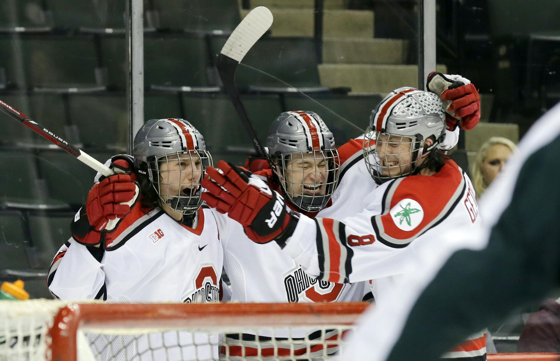 Ohio State forward Tanner Fritz, left, celebrates with forward Max McCormick, center, and defenseman Curtis Gedig (8) after Fritz scored on Michigan State goalie Jake Hildebrand during the second period of an NCAA Big Ten college hockey game in St. Paul, Minn., Thursday, March 20, 2014. (AP Photo/Ann Heisenfelt)
