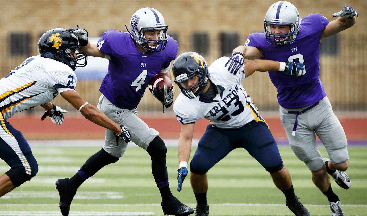 Jack Gilliland (4) stiff arms a defender as Charlie Dowdie (8) blocks during the homecoming football game between UST and Carleton College on Palmer Field at O'Shaughnessy Stadium on October 5, 2013. The Tommies defeated Carleton by a final score of 65-6.