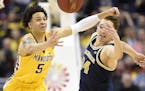 Minnesota guard Amir Coffey (5) fights for the ball with Michigan forward Mark Donnal (34) during the first half of an NCAA college basketball game in