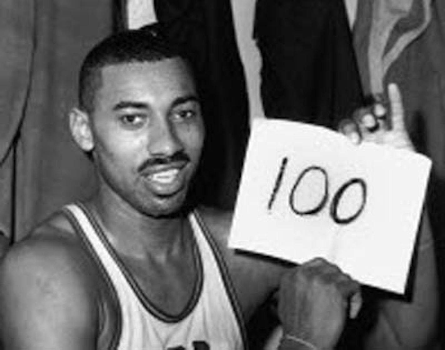 In this March 2, 1962 file photo, Wilt Chamberlain of the Philadelphia Warriors holds a sign reading "100" in the dressing room in Hershey, Pa., after he scored 100 points, as the Warriors defeated the New York Knickerbockers 169-147.