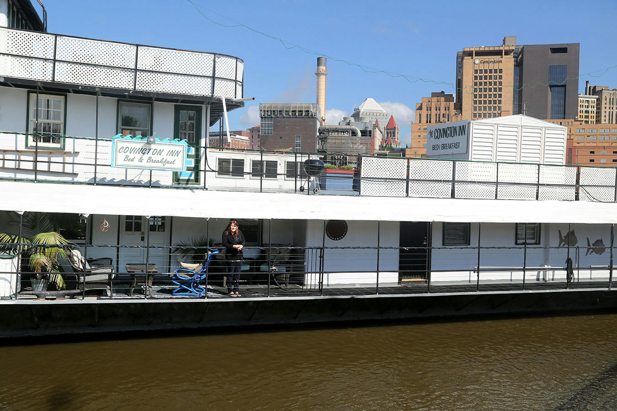 Innkeeper Liz Miller on the deck of The Covington Inn, a floating B&B anchored on Harriet Island. The B&B, which includes four bedroom suites and innkeeper's quarters, is for sale for $529,900.
