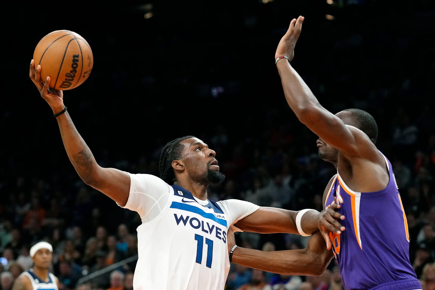 Minnesota Timberwolves center Naz Reid (11) drives against Phoenix Suns center Bismack Biyombo, right, during the first half of an NBA basketball game Wednesday, March 29, 2023, in Phoenix. (AP Photo/Ross D. Franklin)