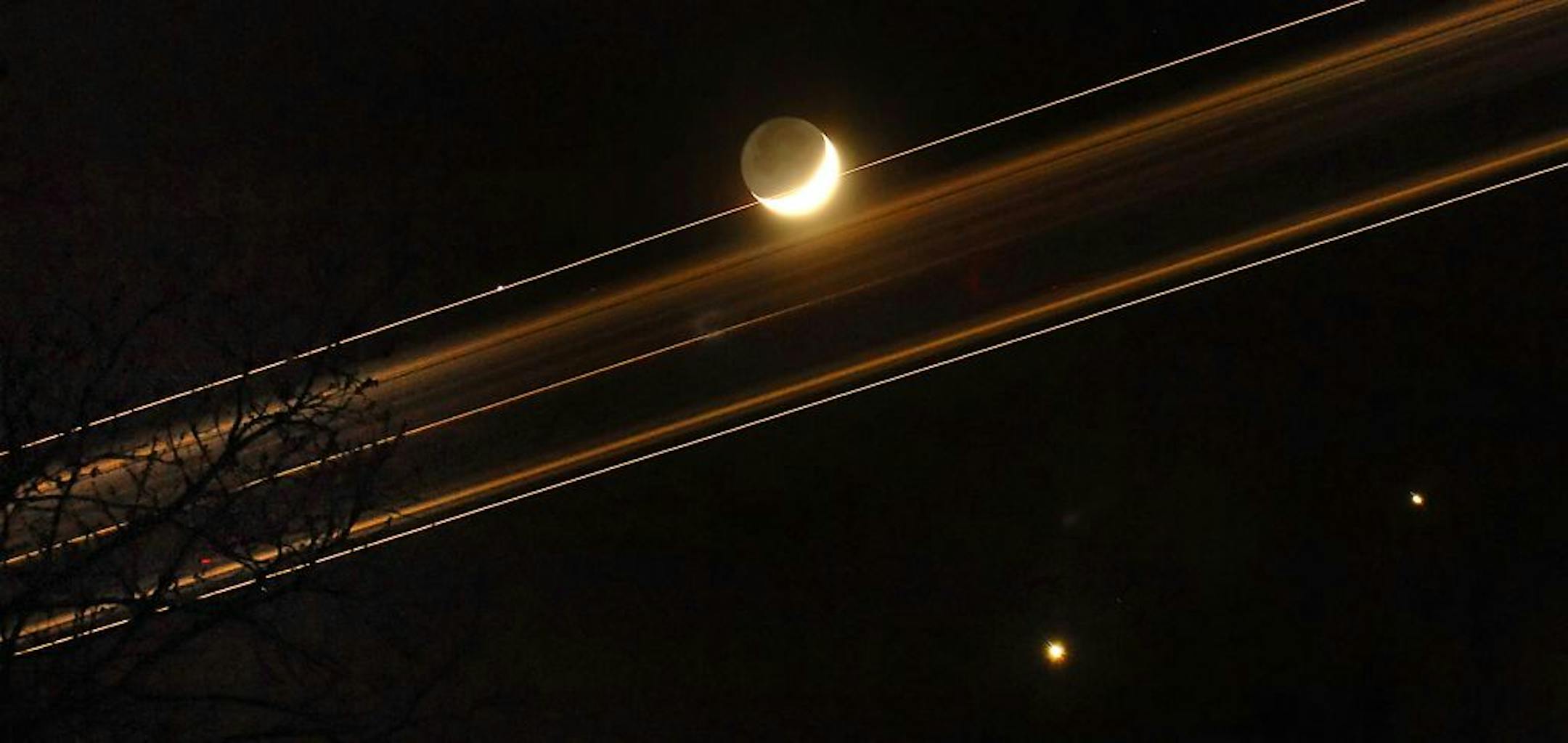 This timed exposure shows a jet streaking across the night sky as it comes in for a landing at Charlotte-Douglas International Airport Monday, Dec. 1, 2008, in Charlotte, N.C. Venus, bottom, and Jupiter, lower right, are edging closer to each other in the southwestern sky joining a crescent moon. The next time the three will be as close and visible as this week will be Nov. 18, 2052, according to Jack Horkheimer, director of the Miami Space Transit Planetarium.
