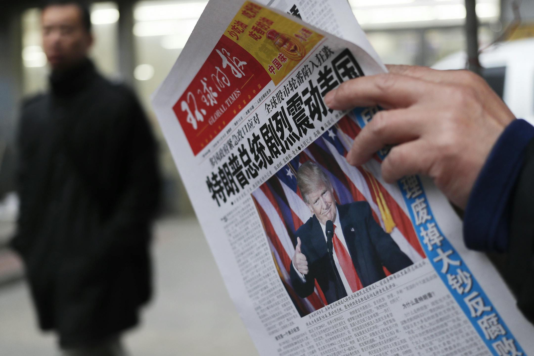 FILE - In this Nov. 10, 2016 file photo, a man reads a newspaper with the headline that reads "U.S. President-elect Donald Trump delivers a mighty shock to America" at a newsstand in Beijing. With Trump's latest tweets touching on sensitive issues, China must decide how to handle an incoming American president who relishes confrontation and whose online statements appear to foreshadow shifts in foreign policy. China awoke Monday, Dec. 5, to criticism from Trump on Twitter, days after it responde