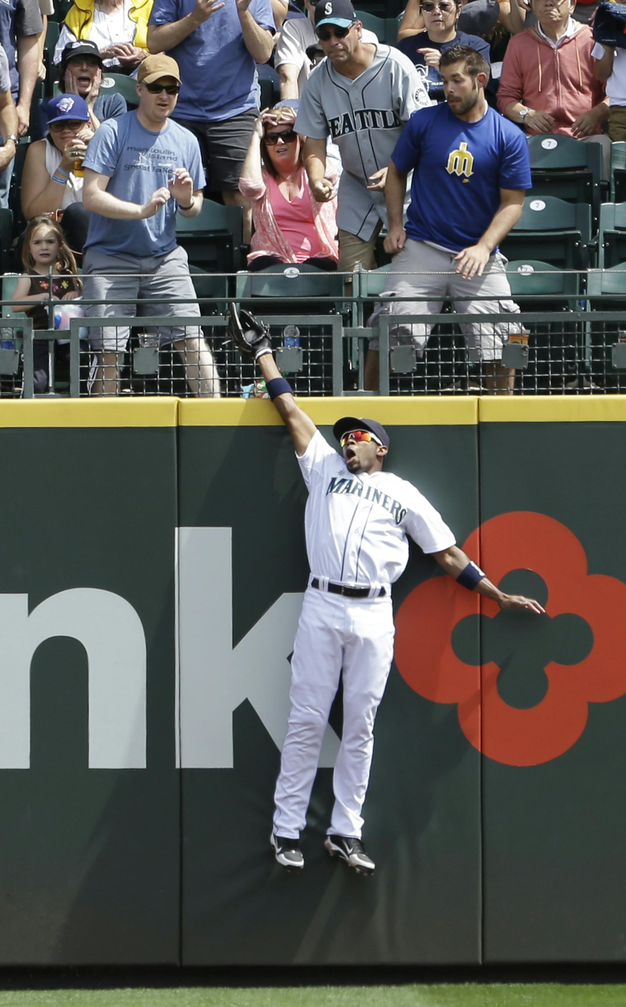 Seattle Mariners right fielder Endy Chavez leaps above the wall to snag a deep fly ball from Minnesota Twins' Chris Colabello in the third inning of a baseball game, Sunday, July 28, 2013, in Seattle. (AP Photo/Elaine Thompson)
