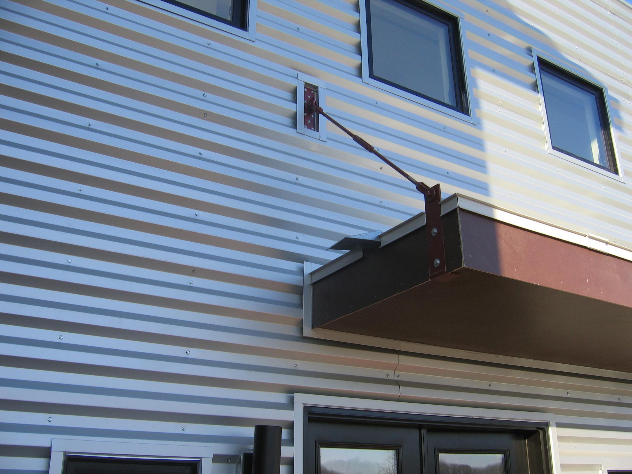 A red turnbuckle was installed that allowed us to have a cantilevered awning that appears to float away from the house.