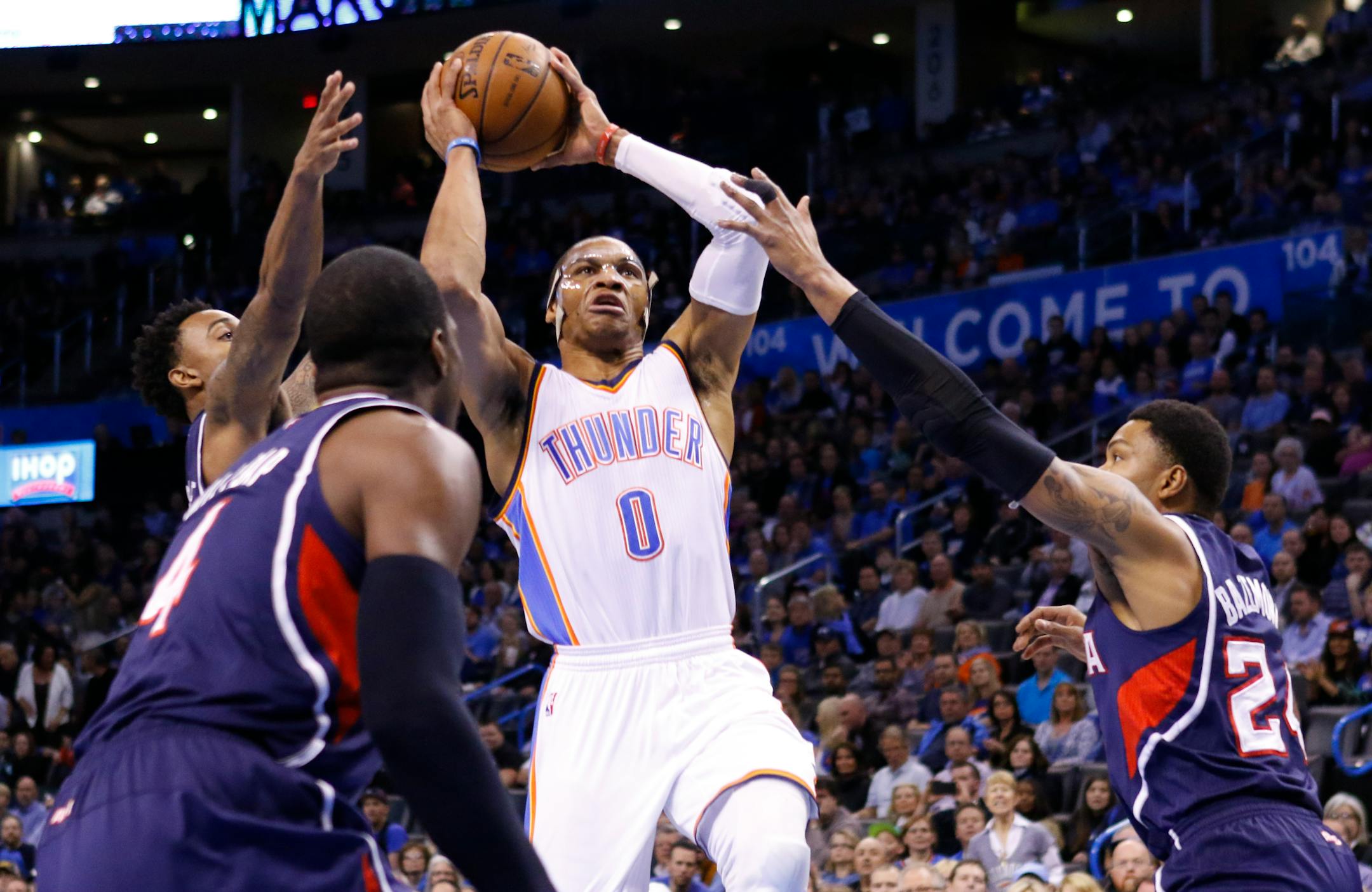 Oklahoma City Thunder guard Russell Westbrook (0) goes to the basket in between Atlanta Hawks guard Kent Bazemore (24) and Atlanta Hawks forward Paul Millsap (4) during the first quarter of an NBA basketball game in Oklahoma City, Friday, March 20, 2015. (AP Photo/Alonzo Adams)