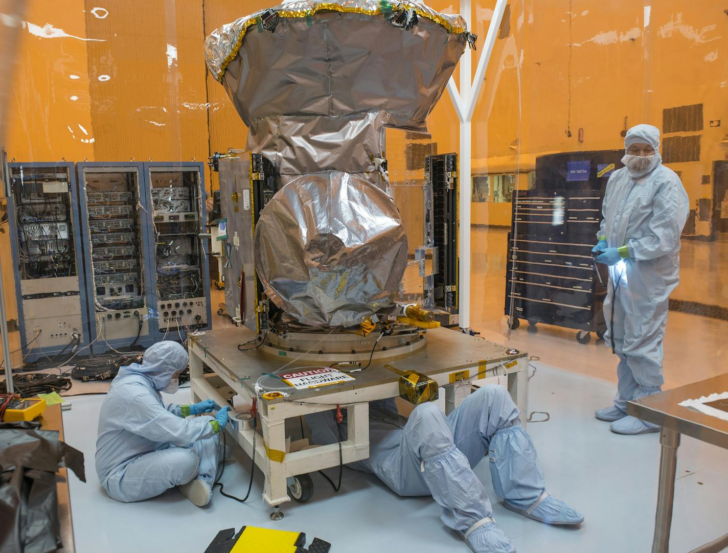 Workers affix a placard to the bottom of the Transiting Exoplanet Survey Satellite, TESS, at Kennedy Space Center in Cape Canaveral, Fla., Feb. 15, 2018. NASA&#x2019;s new spacecraft, to be launched in April, will give scientists a much clearer view of the planets orbiting stars near to us. (Josh Ritchie/The New York Times)