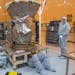 Workers affix a placard to the bottom of the Transiting Exoplanet Survey Satellite, TESS, at Kennedy Space Center in Cape Canaveral, Fla., Feb. 15, 20