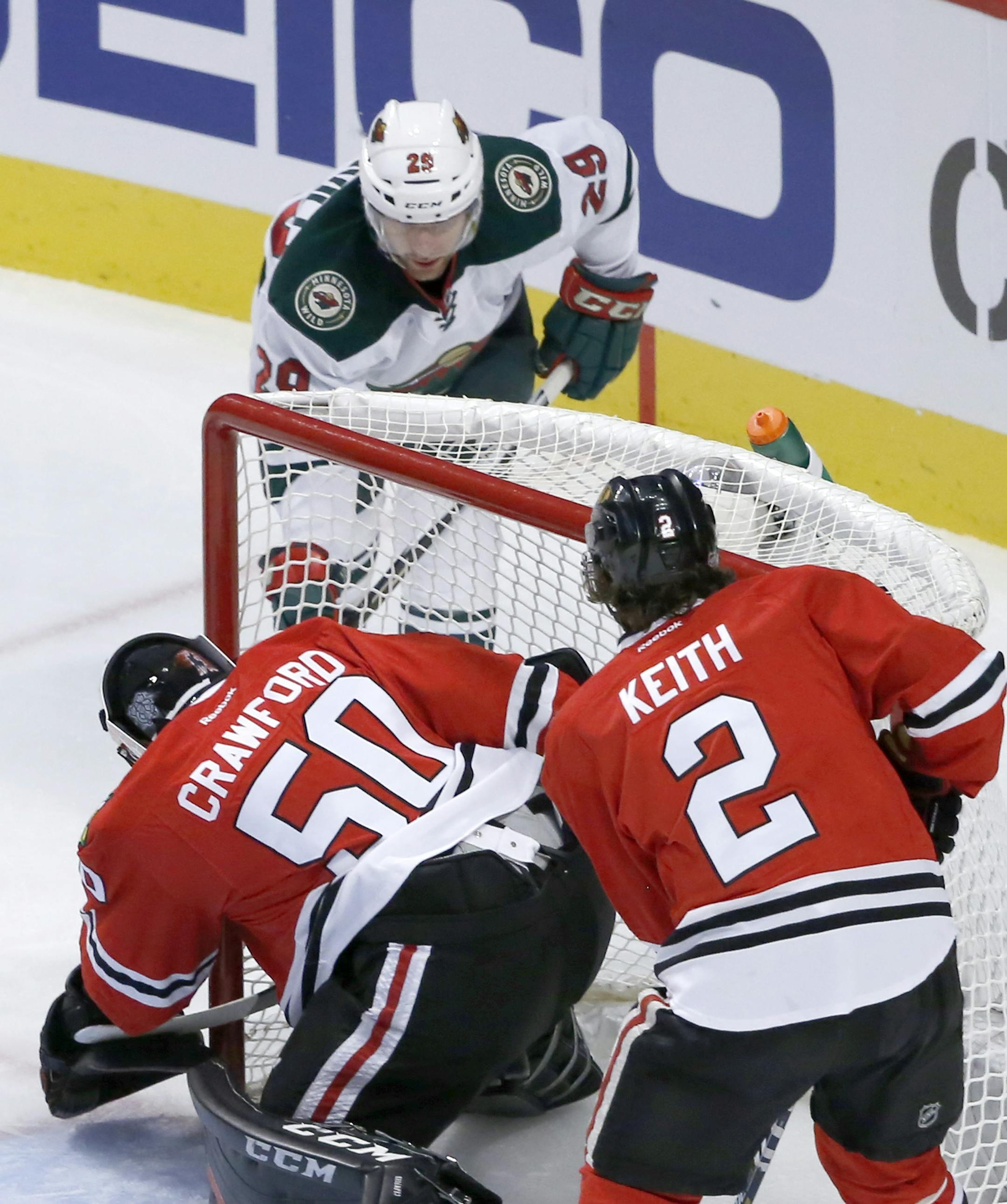 Minnesota Wild right wing Jason Pominville, top, scores past Chicago Blackhawks goalie Corey Crawford as Duncan Keith (2) watches during the first period of an NHL hockey game Tuesday, Dec. 1, 2015, in Chicago. (AP Photo/Charles Rex Arbogast)