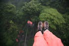Photographer's feet, 100 feet off the ground, looking down at the "Tarzan Swing, 60 feet off the ground, at the Selvatura Zip Line in the cloud forest