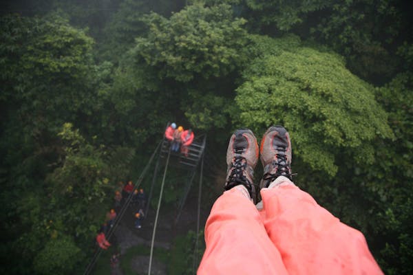 Photographer's feet, 100 feet off the ground, looking down at the "Tarzan Swing, 60 feet off the ground, at the Selvatura Zip Line in the cloud forest