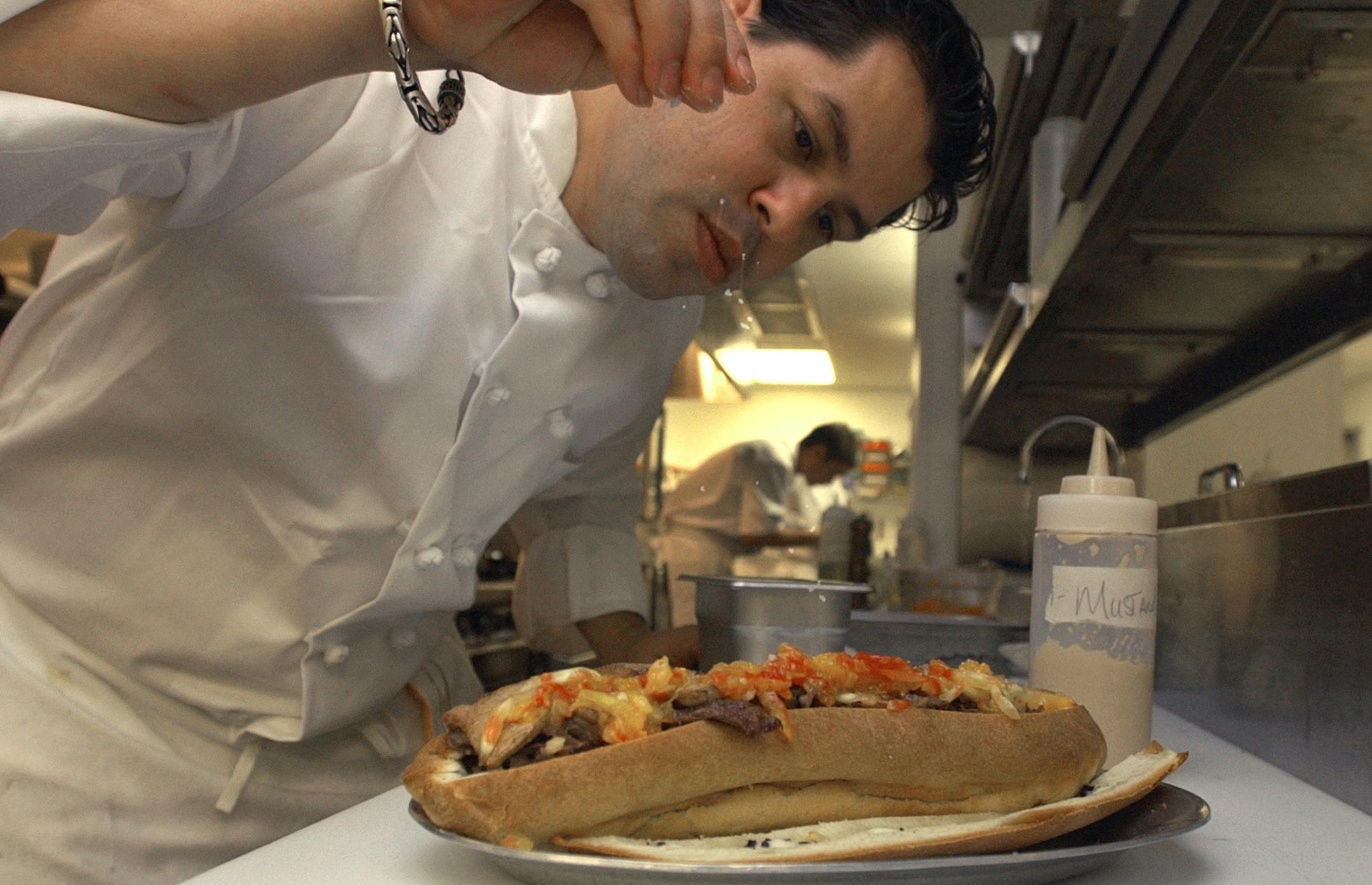 Barclay Prime executive chef Todd Miller sprinkles coarse salt on a cheesesteak at the restaurant in Philadelphia Tuesday Oct. 5, 2004. This version of the traditional Philadelphia sandwich, made with Kobe beef, melted Taleggio cheese, shaved truffles, sauteed foie gras, caramelized onions and heirloom shaved tomatoes on a homemade brioche roll bushed with truffle butter and squirted with homemade mustard, is served with a small bottle of champagne and sells for $100 at Stephen Starr's Barclay P
