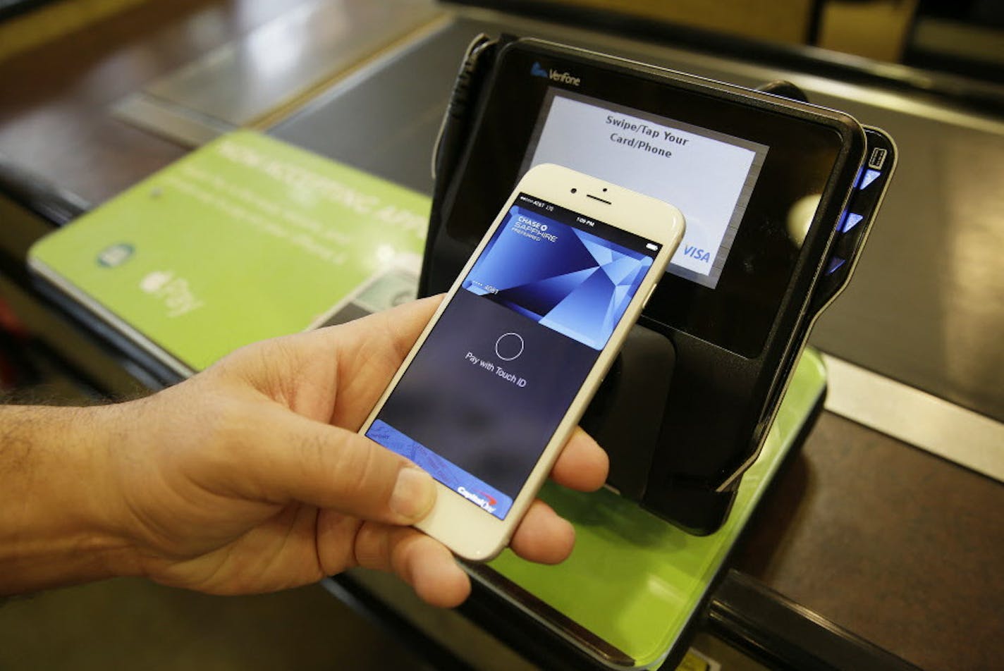 FILE - In this photo taken Friday, Oct. 17, 2014, Eddy Cue, Apple Senior Vice President of Internet Software and Services, demonstrates the new Apple Pay mobile payment system at a Whole Foods store in Cupertino, Calif. Cook on Monday, Oct. 27, 2014 said Apple's new mobile payment system had over 1 million activations in the first three days after it became available, and is now more widely used than any competing payment system. (AP Photo/Eric Risberg, File)