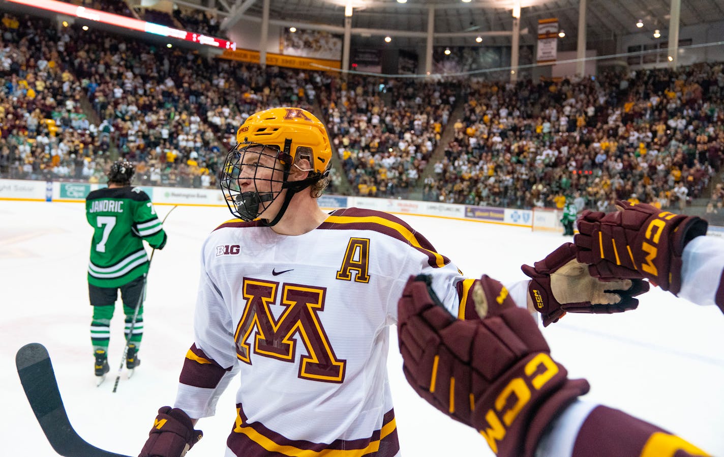 Minnesota defenseman Jackson LaCombe (2) celebrates with his teammates after scoring a goal in the second period Friday, Oct. 21, 2022 at 3M Arena at Mariucci in Minneapolis. ]