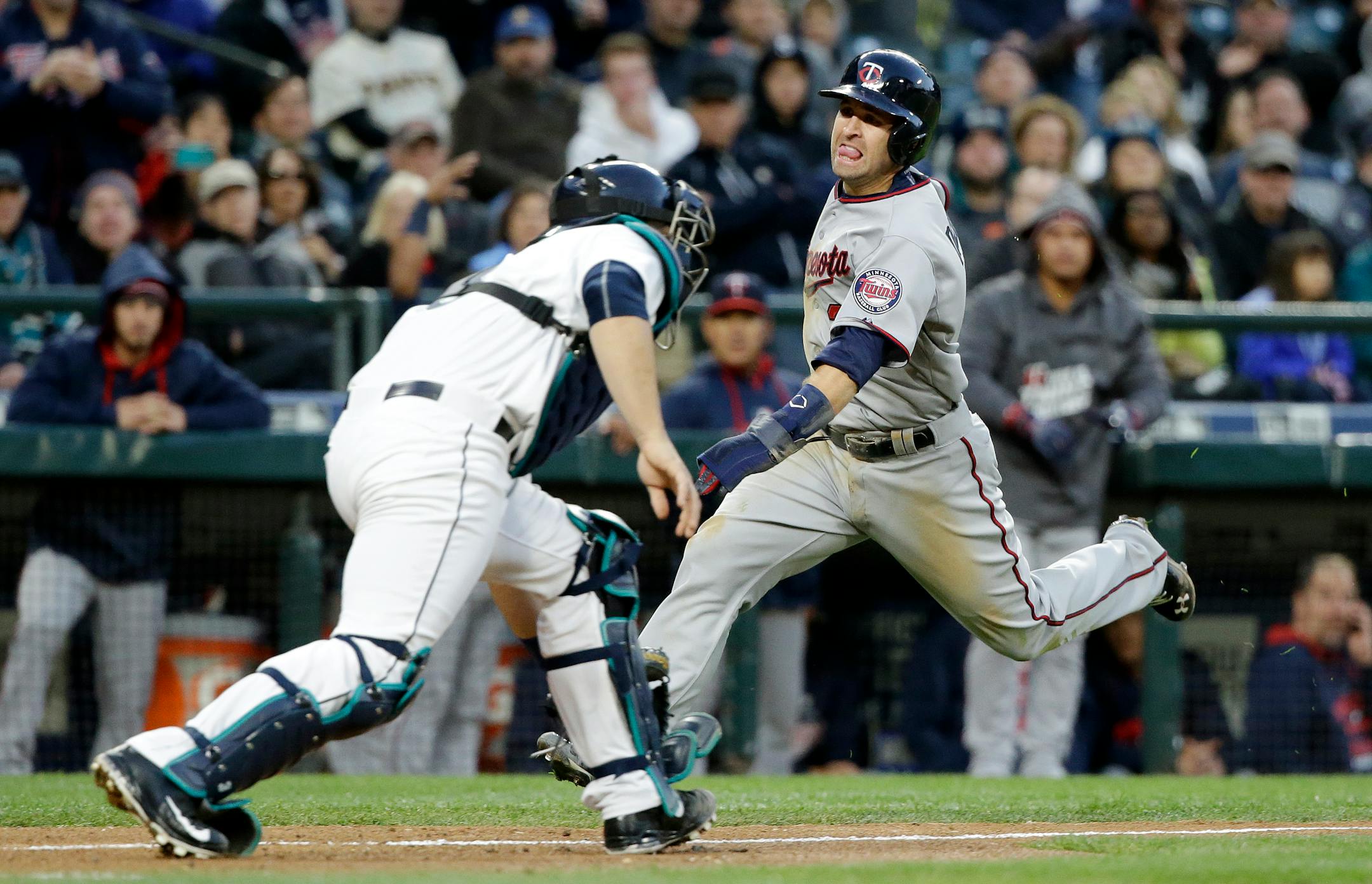 Minnesota Twins' Brian Dozier, right, comes in to score as Seattle Mariners catcher Mike Zunino waits for the ball in the sixth inning of a baseball game Saturday, April 25, 2015, in Seattle. (AP Photo/Elaine Thompson)