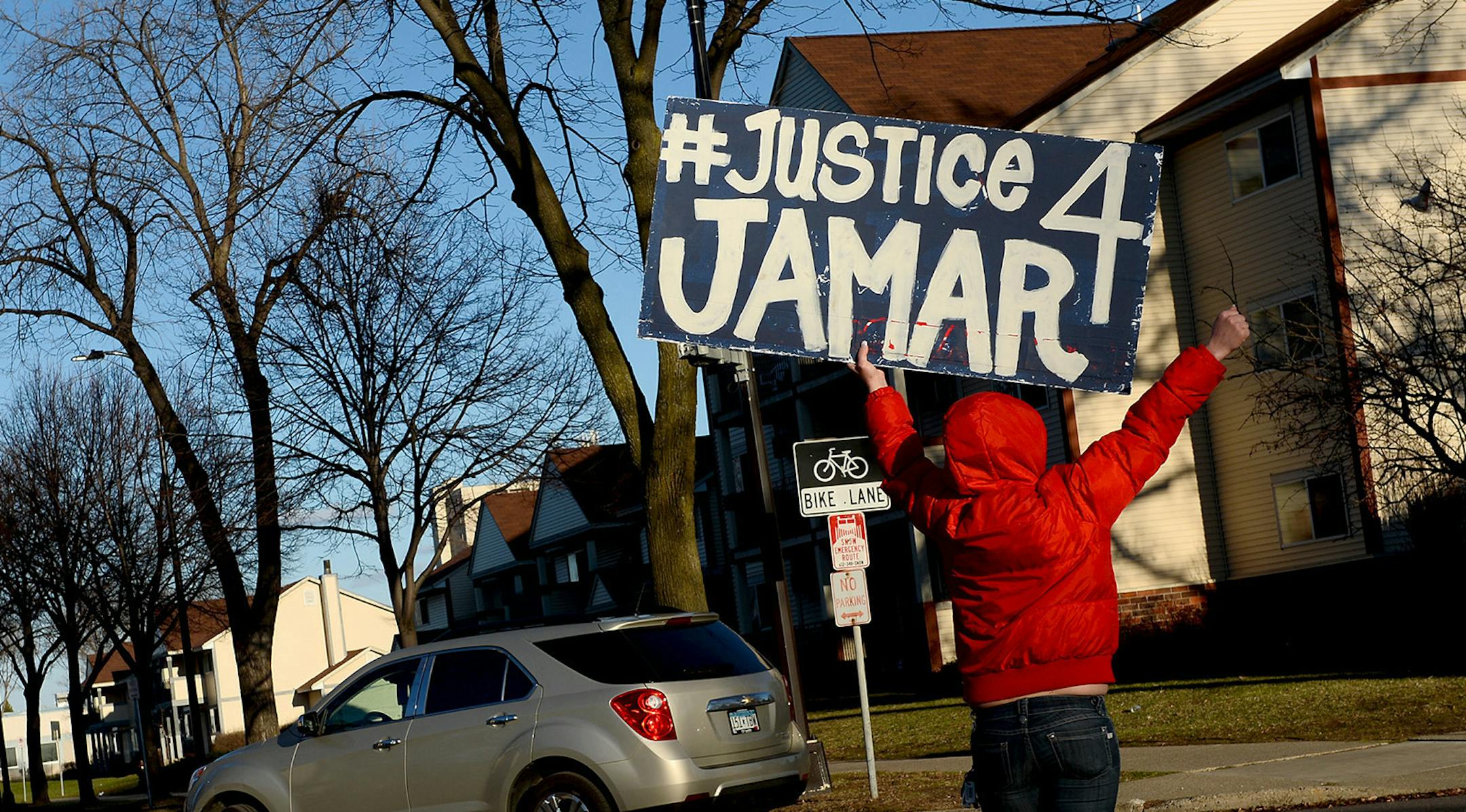 A protestor waved a "Justice 4 Jamar" banner at traffic turning onto Plymouth Avenue Friday afternoon. ] (AARON LAVINSKY/STAR TRIBUNE) aaron.lavinsky@startribune.com A vigil was held at the site of Jamar Clark's memorial on Plymouth Avenue North near James Avenue on Friday, April 1, 2016 in Minneapolis, Minn. ORG XMIT: MIN1604012045480844