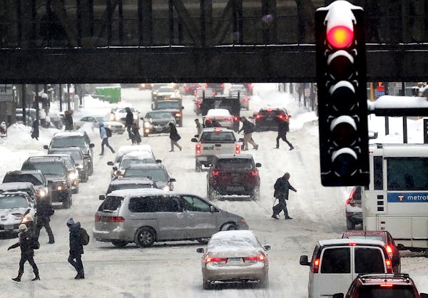 Pedestrians and motorists navigate snowy streets along 3rd Avenue S. in Minneapolis. Several inches of snow fell across the metro area and most of sou