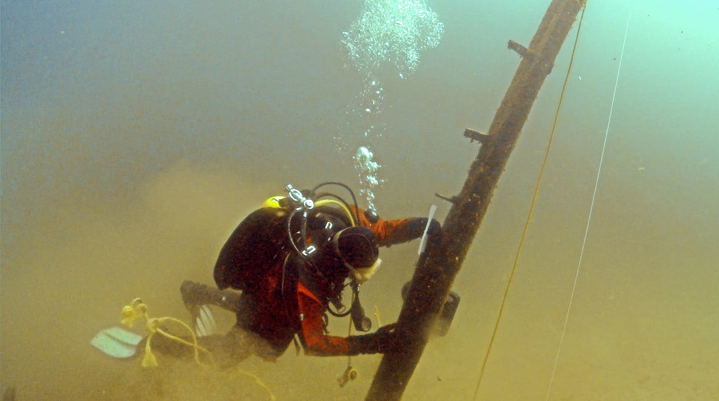 In this photo made June 16, 2013, and provided by Great Lakes Exploation Group, diver Jim Nowka of Great Lakes Exploration Group inspects a wooden beam extending from the floor of Lake Michigan that experts believe may be part of the Griffin, a ship that sank in 1679. Crews are digging a pit at the base of the beam to see if it's attached to a buried ship. (AP Photo/David J. Ruck, Great Lakes Exploration Group)