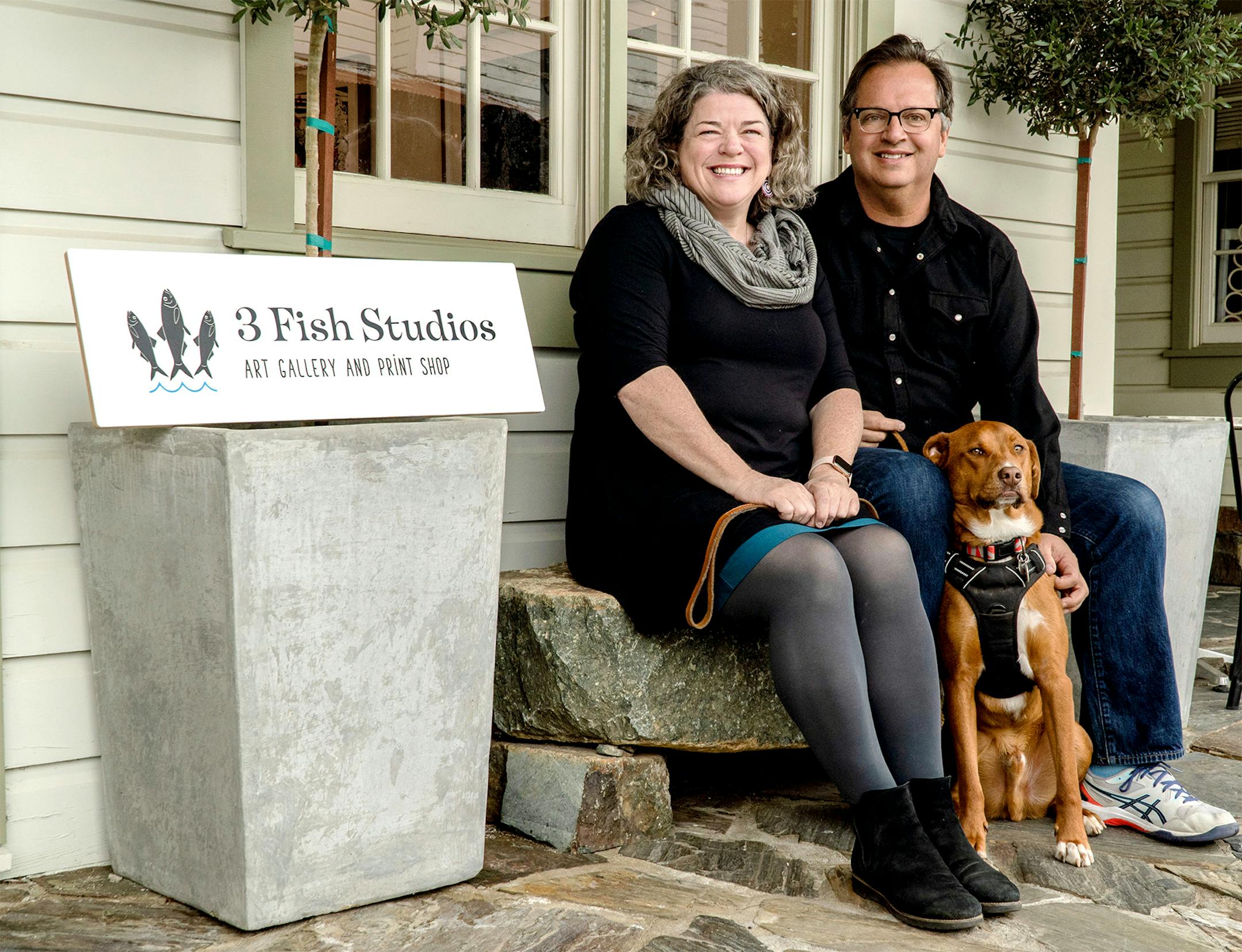 Husband and wife artist team Annie Galvin, left, and Eric Rewitzer pose with their dog Woody in front of their new 3 Fish Studios art gallery in Amador City, Calif., in 2023.