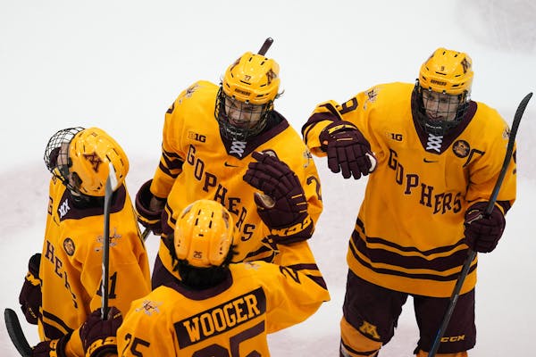 Gophers forward Blake McLaughlin (27) was congratulated by his teammates after he scored the game-winning goal on Dec. 28.
