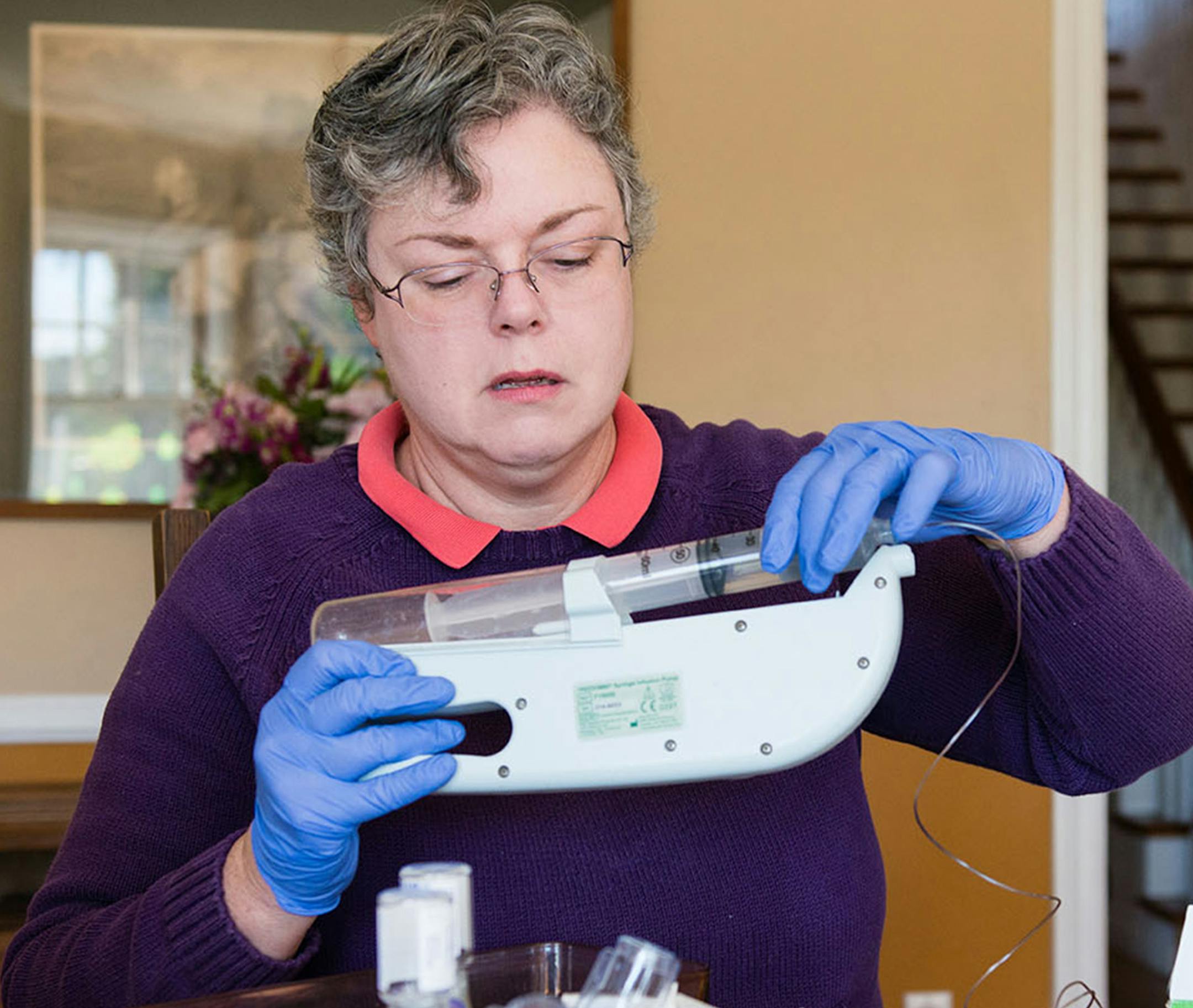 Colleen Tuite sits at her kitchen table and prepares her son's blood-factor infusion on Feb. 23, 2018. (Heidi de Marco/KHN)