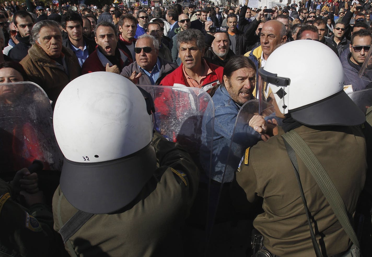 Anti-austerity protesters scuffle with riot police during a student parade in Athens, on Friday, Oct. 28, 2011. The student march, in commemoration of the 71st anniversary of Greece's entry into World War II, went on without major incident, but in other cities officials were heckled and in Thessaloniki, Greece's second city, a military parade was canceled.