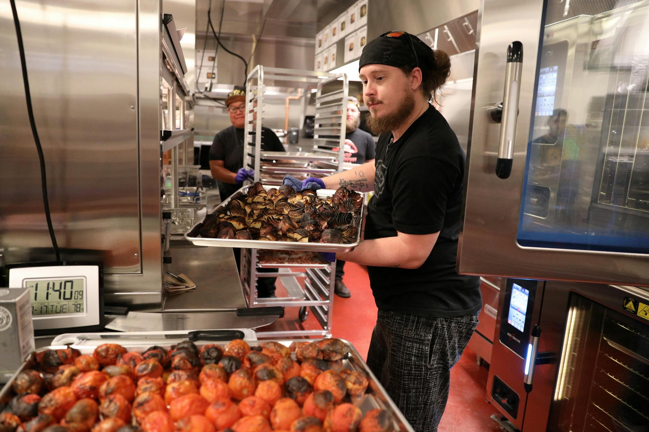 Expo corporate trainer Justin Boggs pulled pans of roasted tomatoes and onions from the oven as he trained a group of new hires in the kitchen at Alamo Drafthouse Cinema.