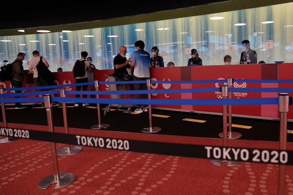 People arriving for the 2020 Summer Olympics wait for their credentials to be validated before they can leave Haneda Airport in Tokyo on Monday.