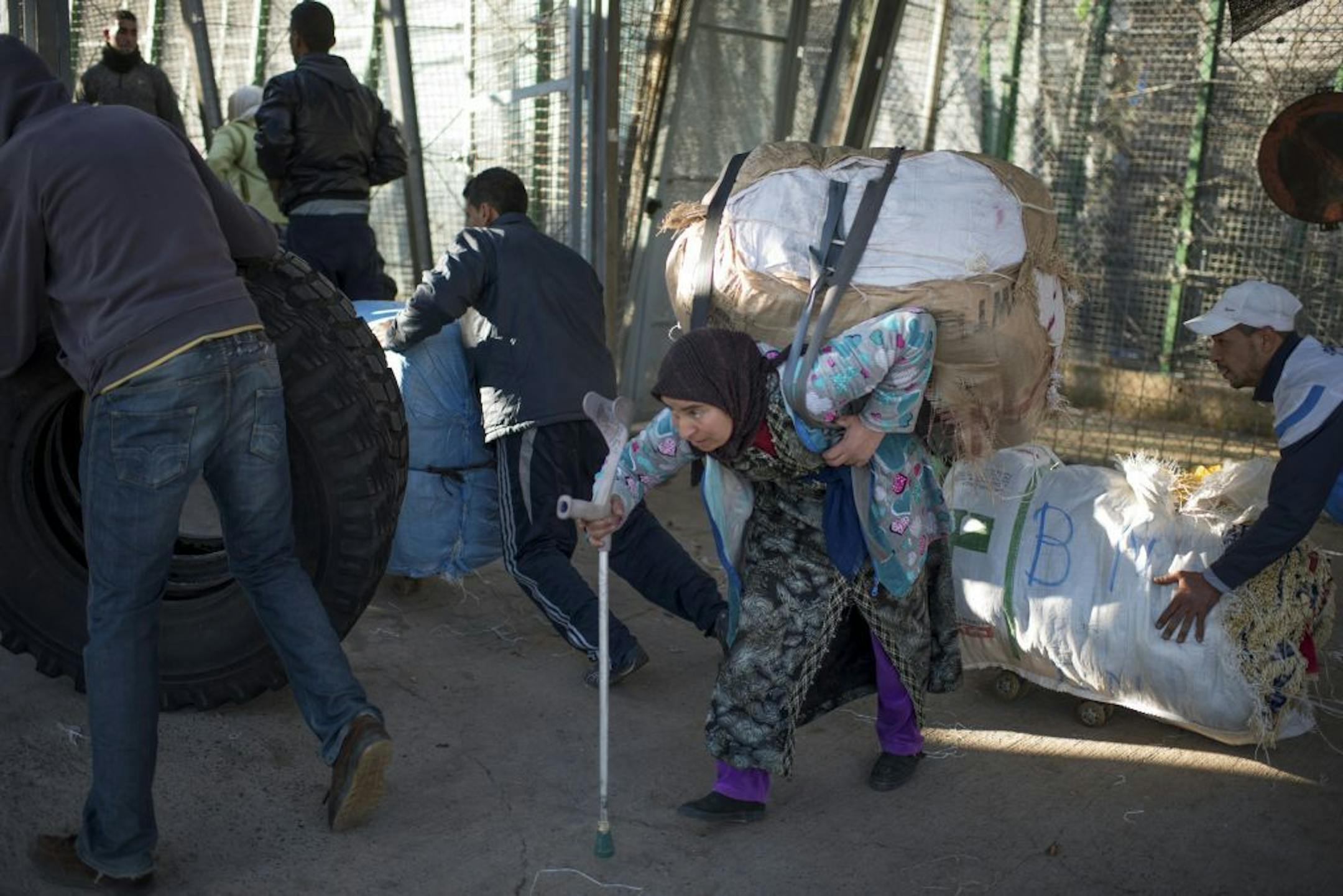 A Moroccan woman carries a large package on her back as hundreds of people rush to cross the Moroccan-Spanish border, in Melilla, Spain, Jan. 21, 2014. Known as "mule ladies," hundreds of Moroccan women transport packages across the border for traders looking to avoid the country's import tax.