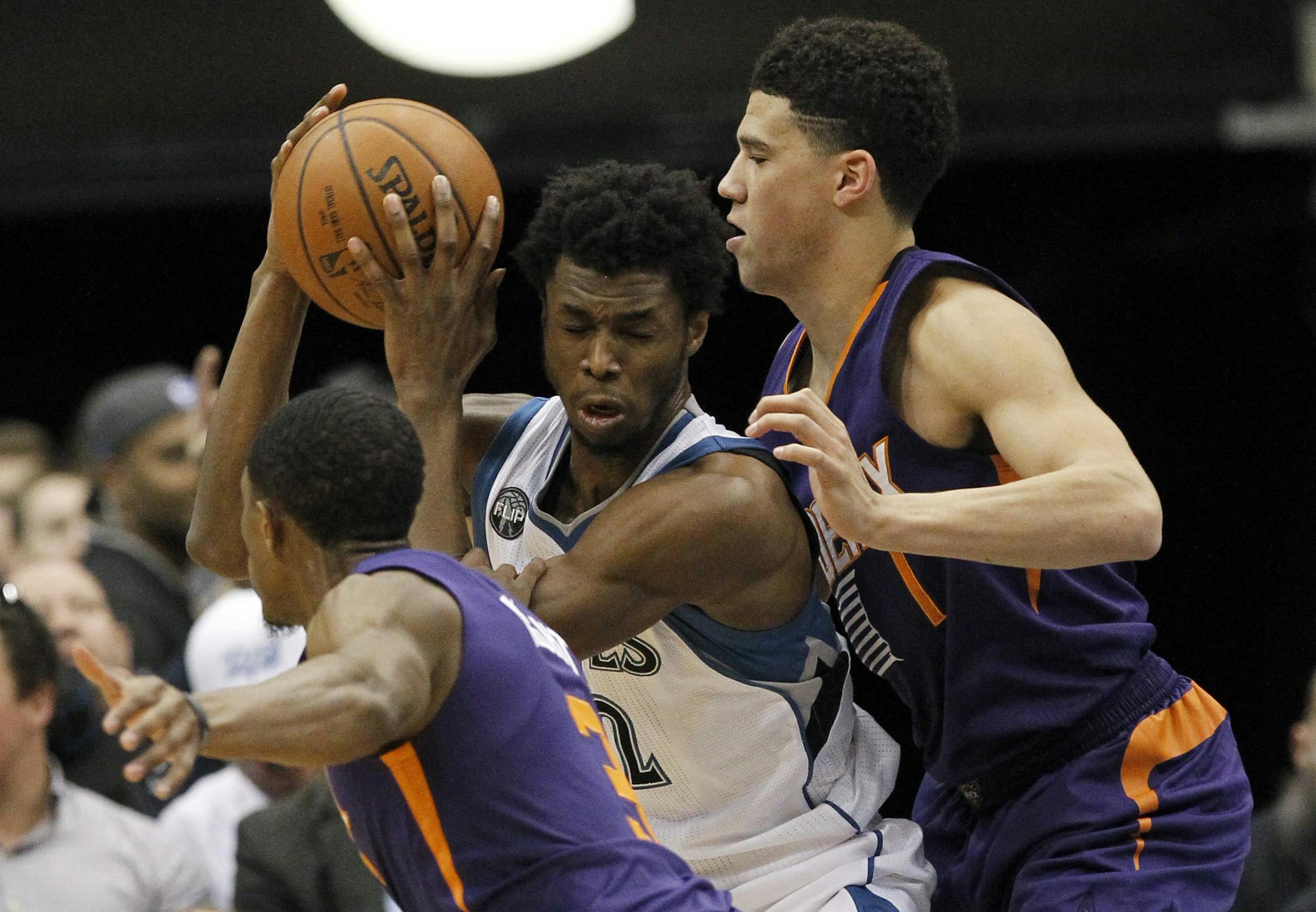 Timberwolves guard Andrew Wiggins, center, split the defense of Suns guard Devin Booker, right, and Brandon Knight during the first half Monday.