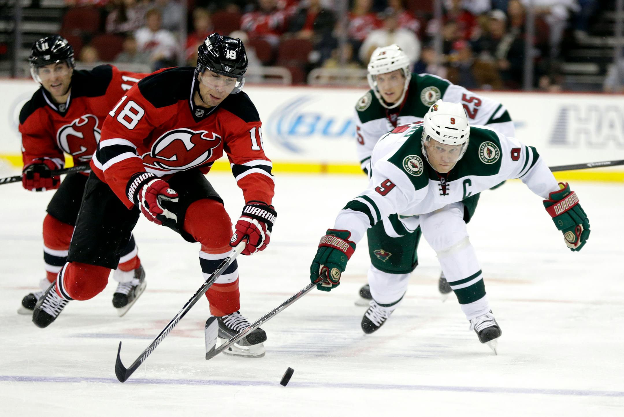 New Jersey Devils right wing Steve Bernier (18) and Minnesota Wild center Mikko Koivu (9), of Finland, reach for the puck during the second period of an NHL hockey game, Tuesday, Nov. 11, 2014, in Newark, N.J. (AP Photo/Julio Cortez)