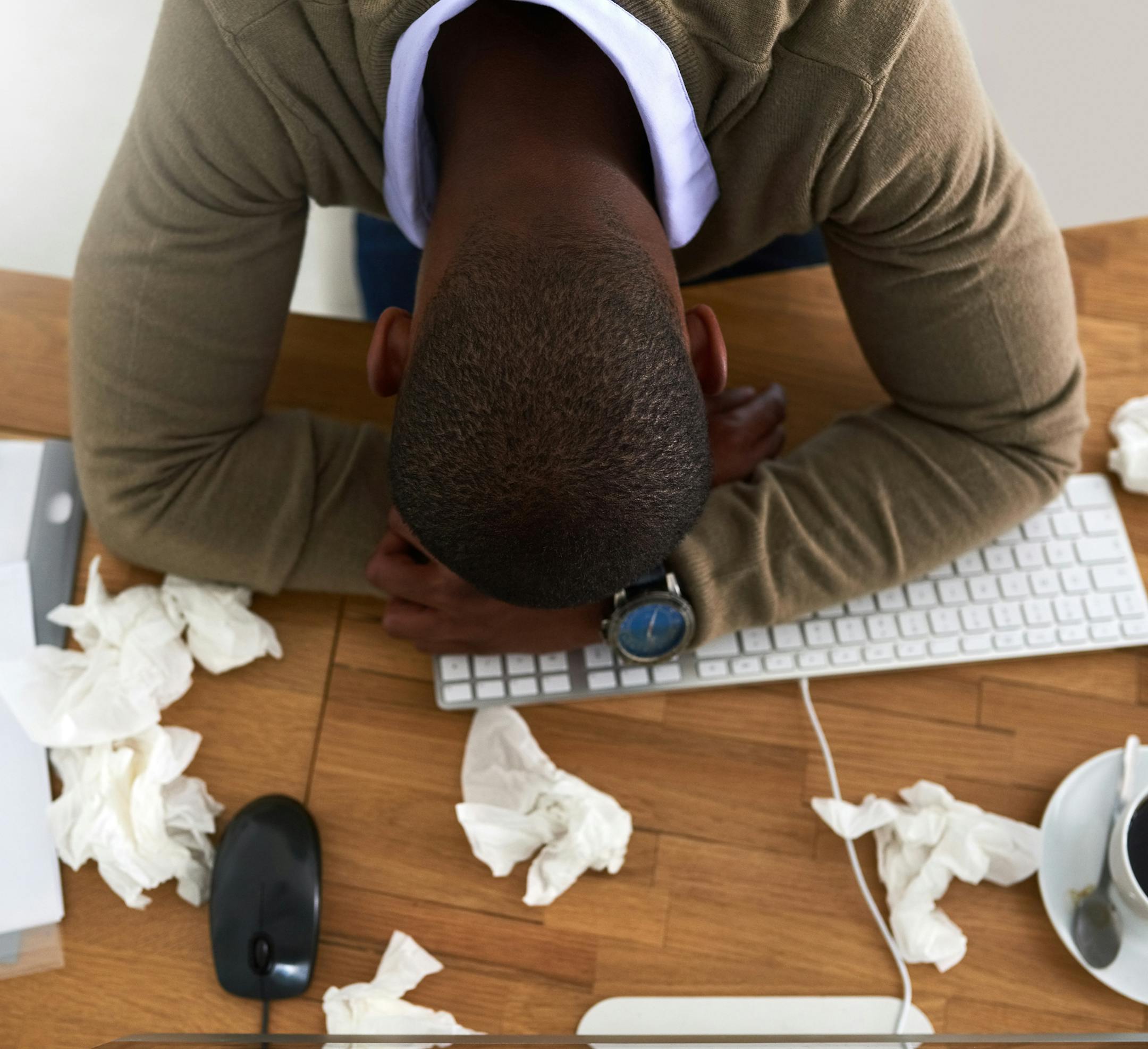 High angle shot of a young businessman feeling ill at his work desk