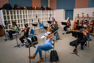 Adrianna Togba, center, and the rest of the eighth grade orchestra get ready to play a song during class at Jackson Middle School in Champlin.