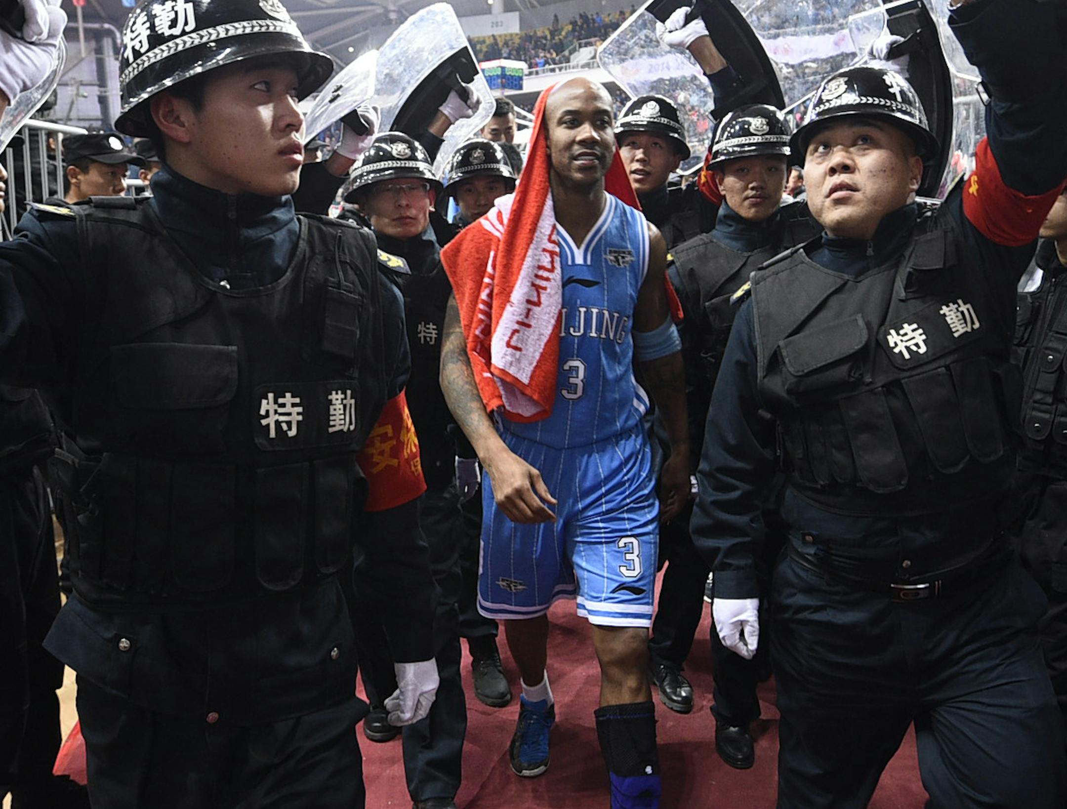 In this photo taken Sunday Nov. 30, 2014, Chinese security guards hold up shield to protect Beijing Ducks' Stephon Marbury during a CBA match between his team and Shanxi Dragons in Taiyuan in northern China's Shanxi province. After a tumultuous career in the NBA, Stephon Marbury says he’s found peace in China, thriving on the court with the Beijing Ducks, mentoring young Chinese teammates and becoming one with his adopted home town. Now he has an even bigger goal in mind, to one day coach