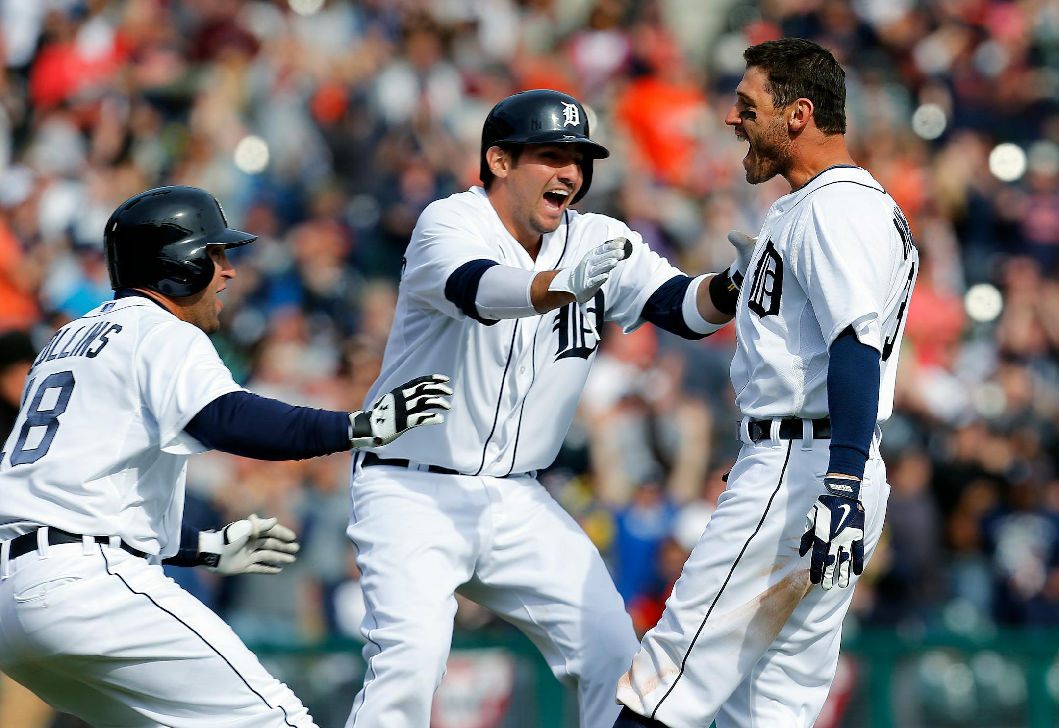 Detroit Tigers' Ian Kinsler, right, celebrates hitting a walkoff-single with teammates Tyler Collins, left, and Nick Castellanos against the Kansas City Royals in the 10th inning of a baseball game in Detroit, Wednesday, April 2, 2014. Detroit won 2-1. (AP Photo/Paul Sancya)